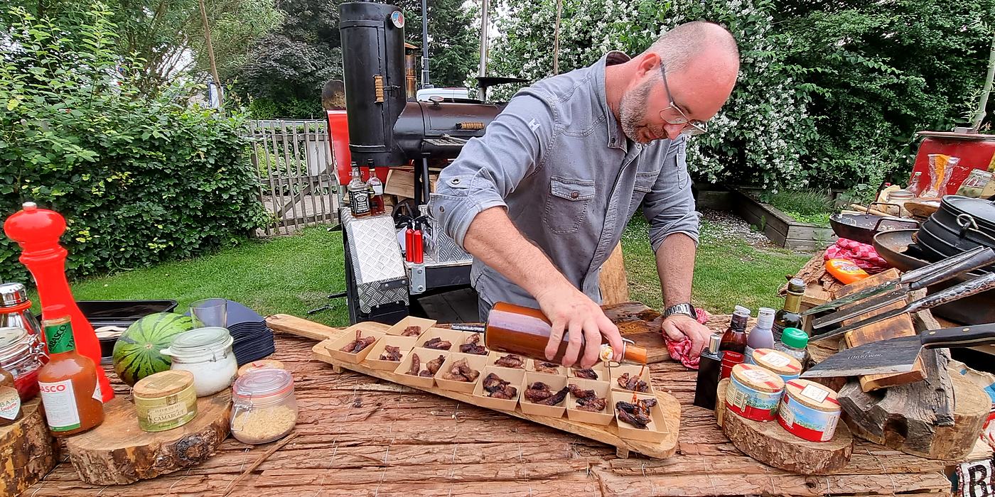 Michael maakt hapjes op aan een buitentafel voor de smoker
