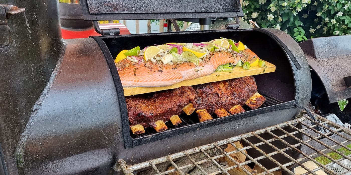 Zalm en ribs op het rooster van een open smoker