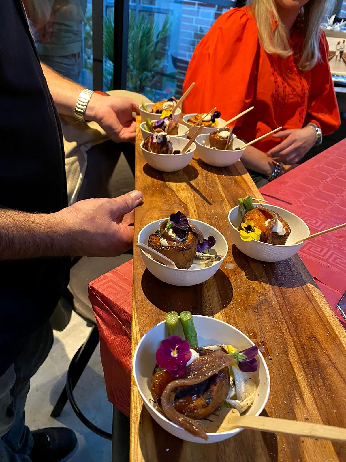 Gasten pakken streetfood-schaaltjes van een lange houten plank